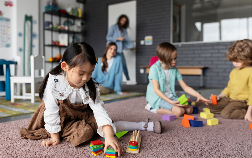 young asian girl playing with blocks with students and educators in the background