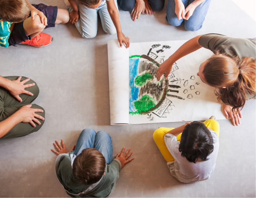 Overhead shot of educator drawing on large pad as children look on