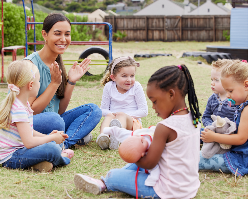 Educator clapping while children sit in a circle on the grass