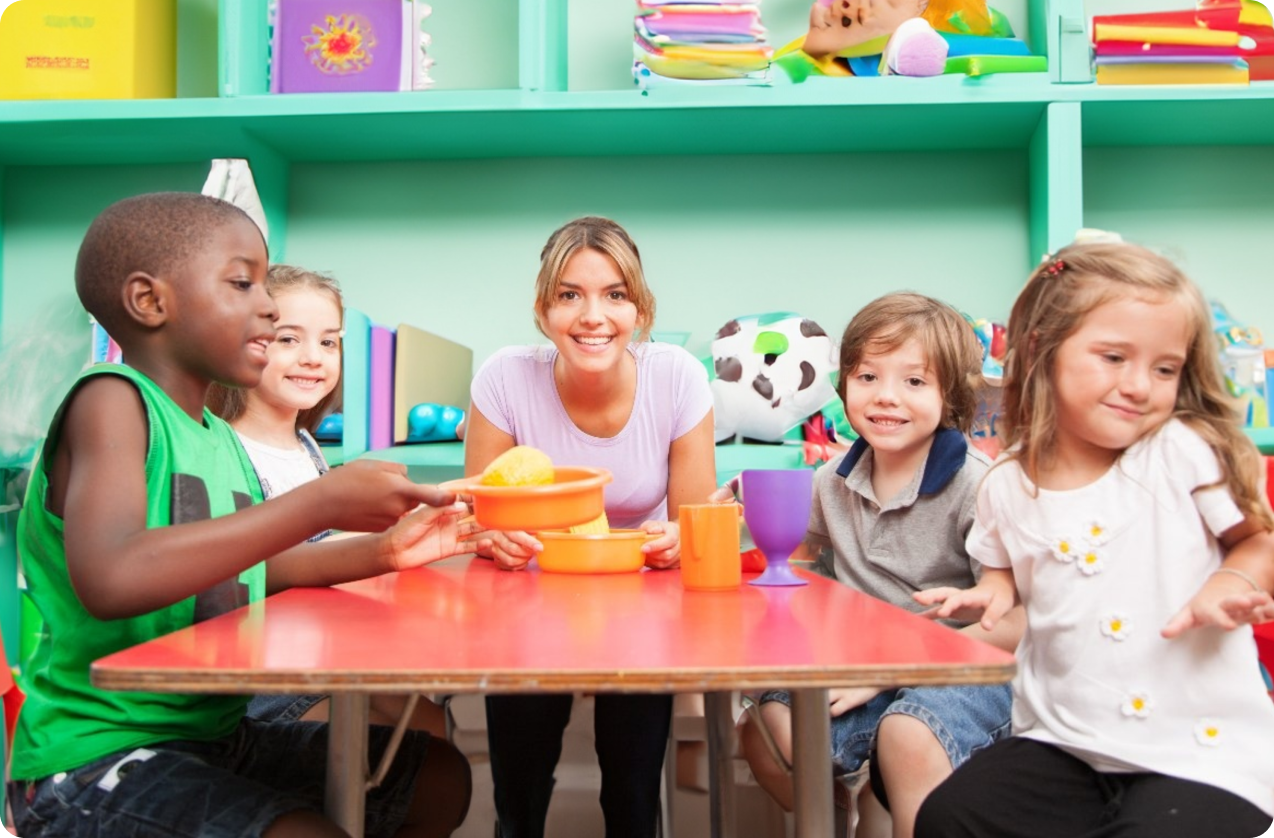 Female educuator smiling at table with 4 children