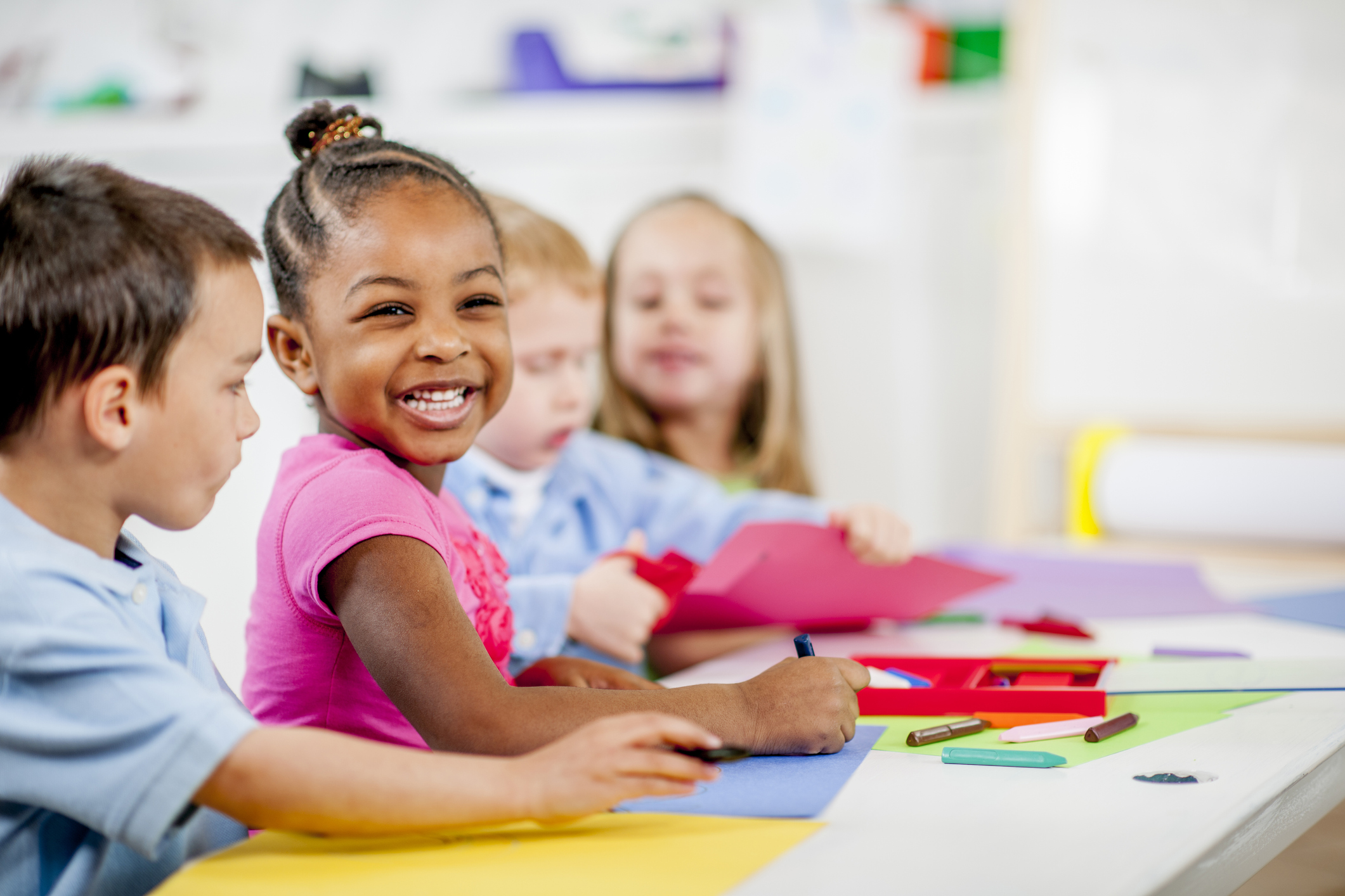 A portrait of a child smiling in a classroom setting