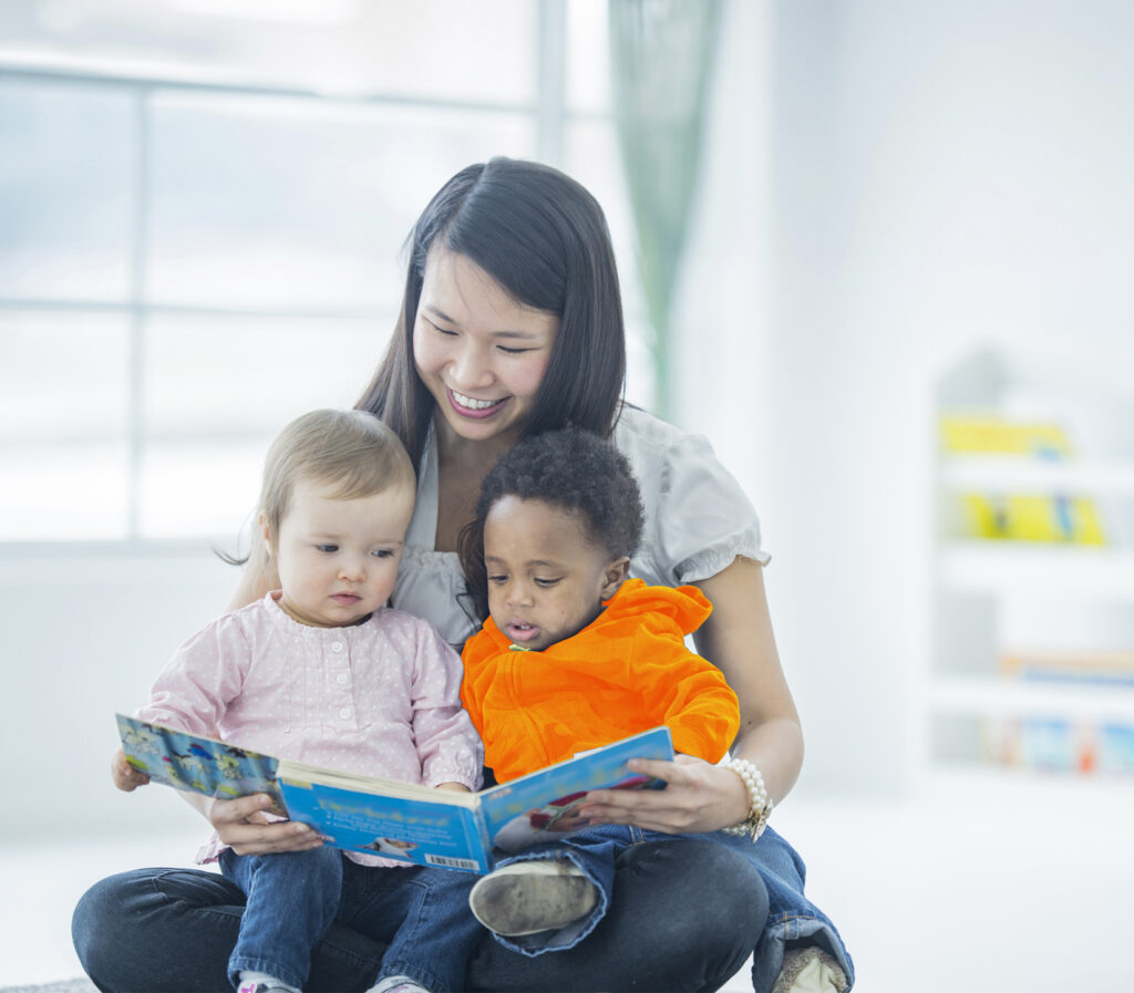 Female educator reading to two children on her lap