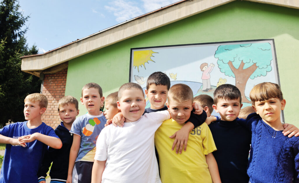 Several children with their arms around each other, showing support for each other (one of several strategies for preventing teacher burnout in early childhood education)