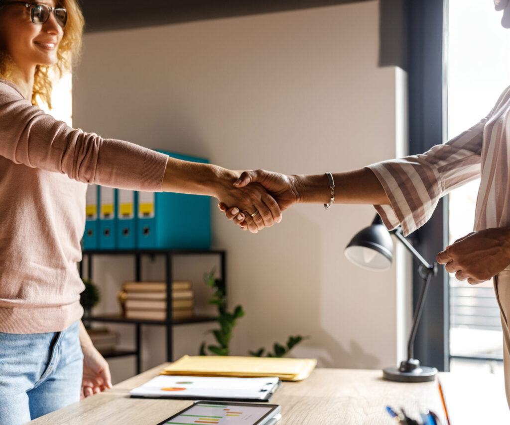 Two people shaking hands over a desk, perhaps after agreeing to use Xero to automate admin