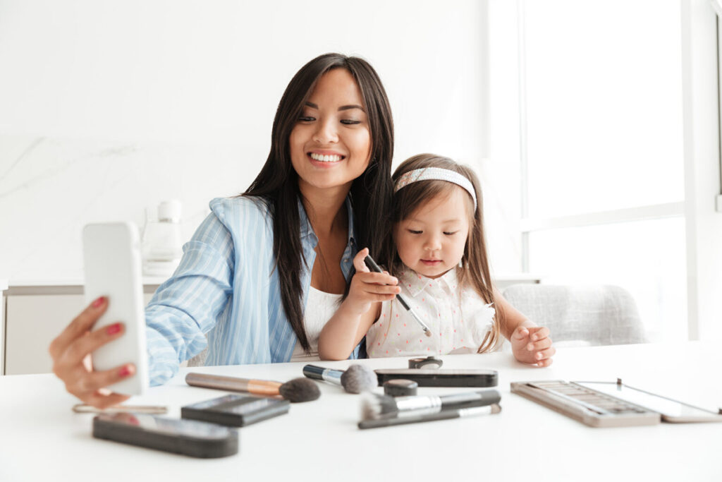 A child sits on her mother's lap while the mother looks at her phone, perhaps using Home, the Xplor Education wraparound care app for families