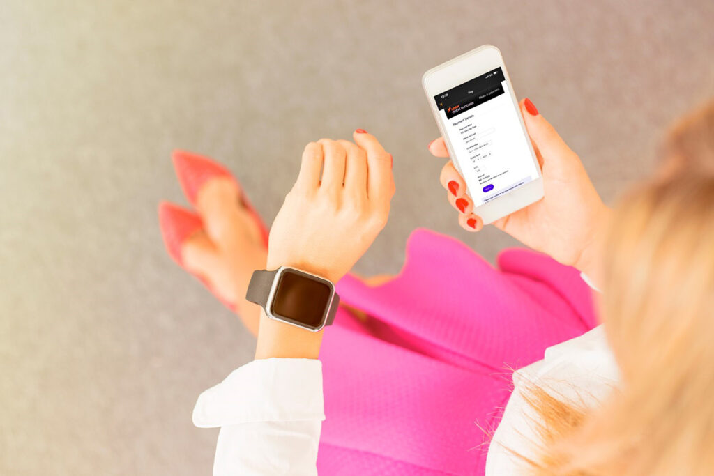 An overhead shot of a woman looking down at her phone with the Xplor Pay integrated payments system app on the screen.