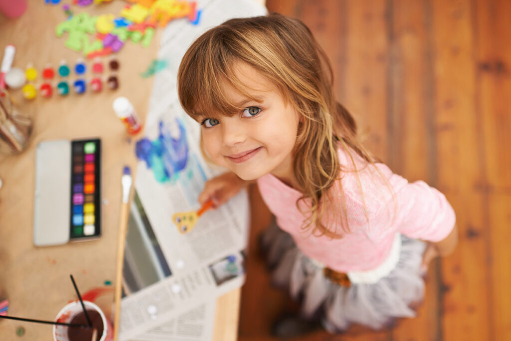 A young girl, looking up at the camera with a slightly mischievous smile