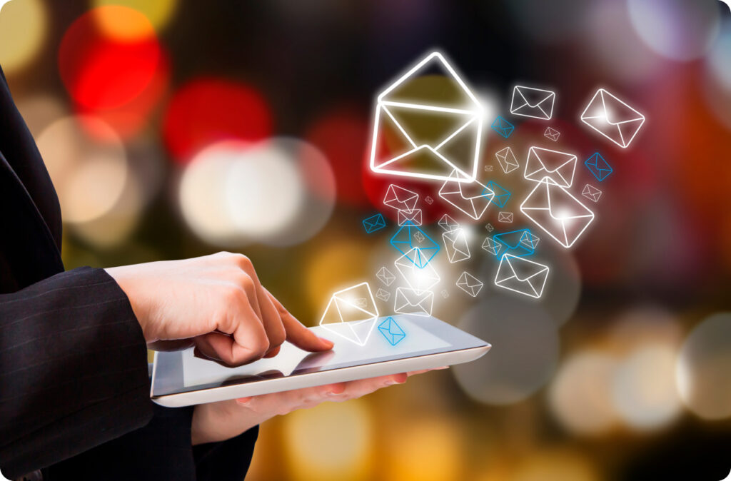 A woman taps tablet as email icons flow from the screen.