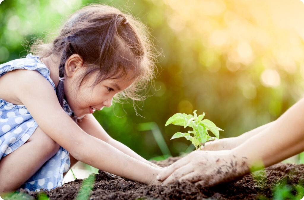 A young girl planting something in a garden, a great way to teach you children about the importance of sustainability.