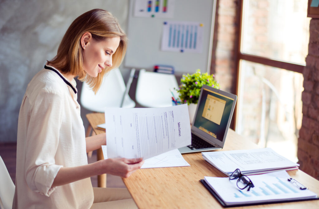 A woman is reading documents at her desk in the office
