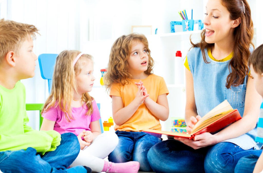 A teacher reading a children's book by an Australian author with four children as they sit on the floor