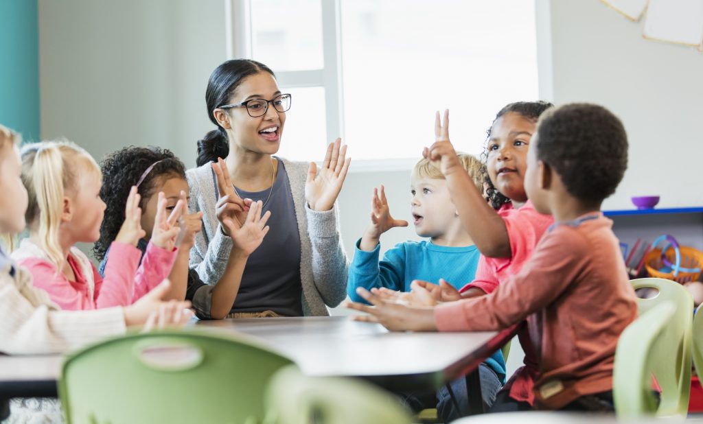 Several children sitting around a table as the educator listens actively, a great way to improve Quality Area 5 ratings