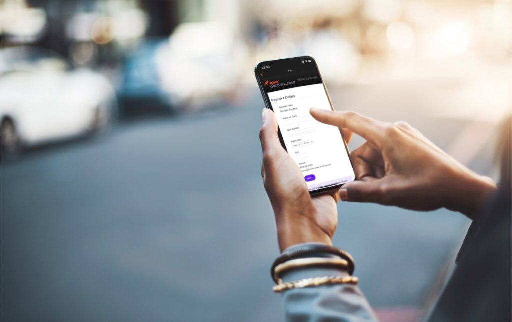 Closeup view of a hand with the Xplor Pay childcare payment software on a mobile device