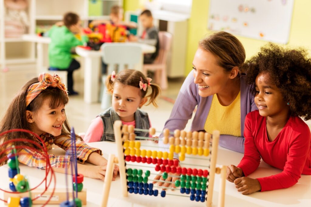 A teacher teaching three children how to use the abacus