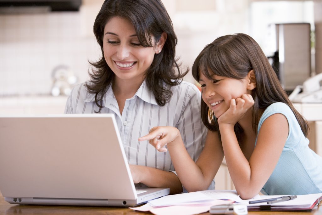 A mother and daughter smiling as they look at a laptop screen