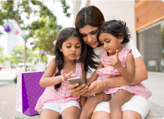 Two young girls, sitting on their mother's lap, looking at a phone, perhaps viewing an Xplor Pay statement