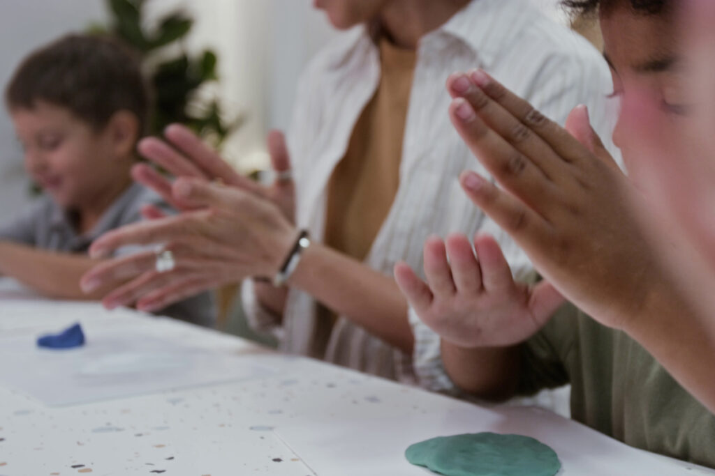 A close up, slightly blurred image of children and educator playing with Playdough