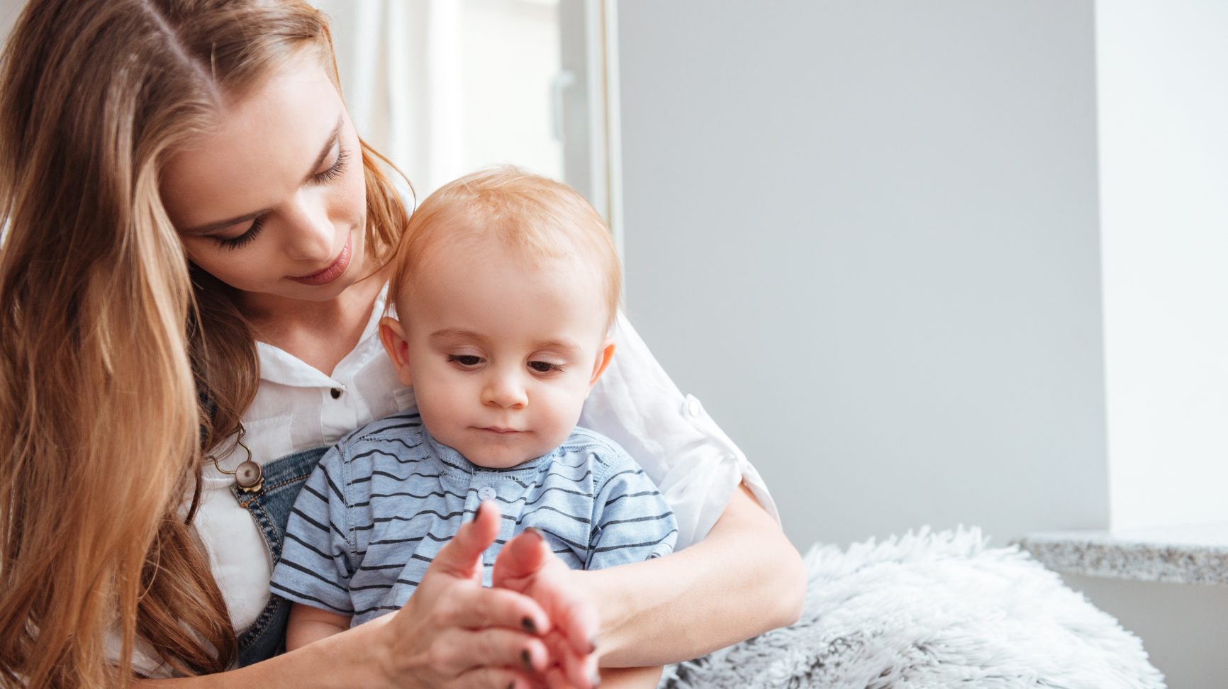 A woman with a baby on her lap, clapping—a form of playful learning