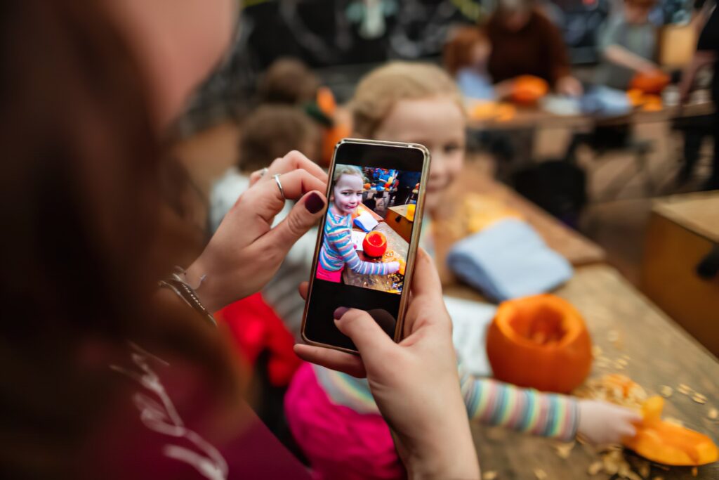 An educator recording a child carving a pumpkin—video documentation is a great way to boost family engagement