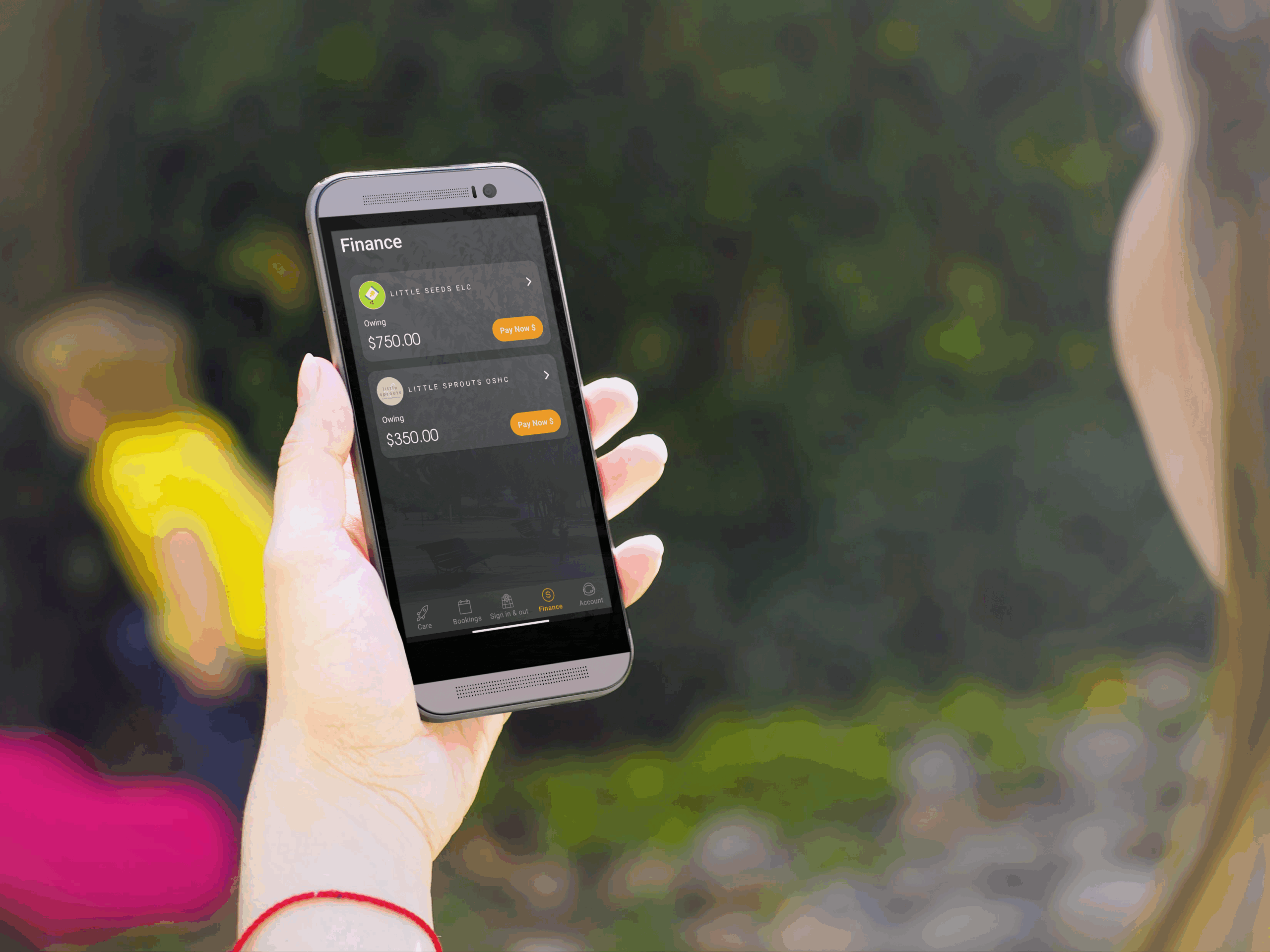 A woman holding a phone showing the Xplor Pay interface—collecting the eDDR can be part of digital enrolments in Office