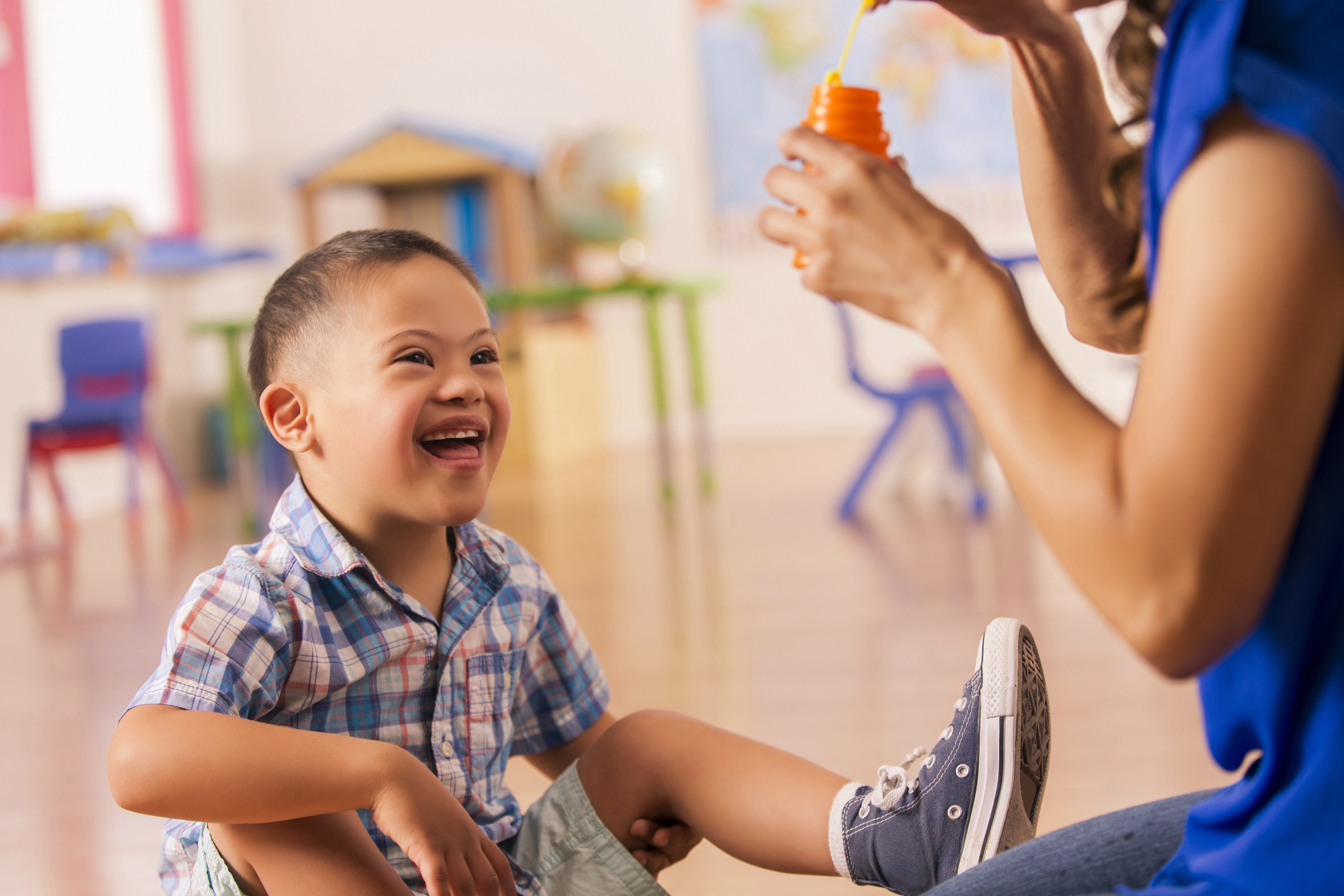 A young boy smiling while an educator blows bubbles