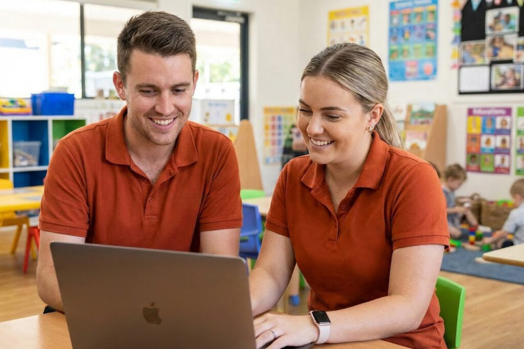 A male and female educator working on a laptop together, perhaps trying to determine the best ways of navigating AI in ECEC